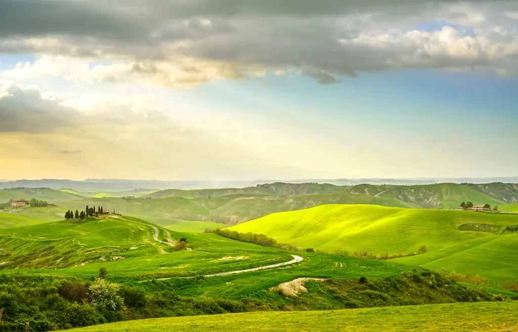 Paisagem verde exuberante com colinas onduladas e casas típicas na região da Toscana, Itália