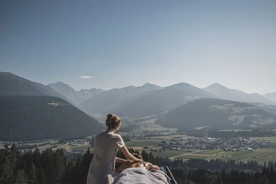 Mulher recebendo massagem ao ar livre com vista panorâmica para as montanhas das Dolomitas, no norte da Itália.