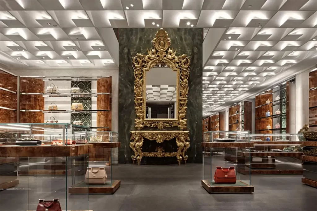 Interior luxuoso da loja Dolce & Gabbana com bolsas em destaque e espelho barroco, refletindo a essência da Moda Italiana.

