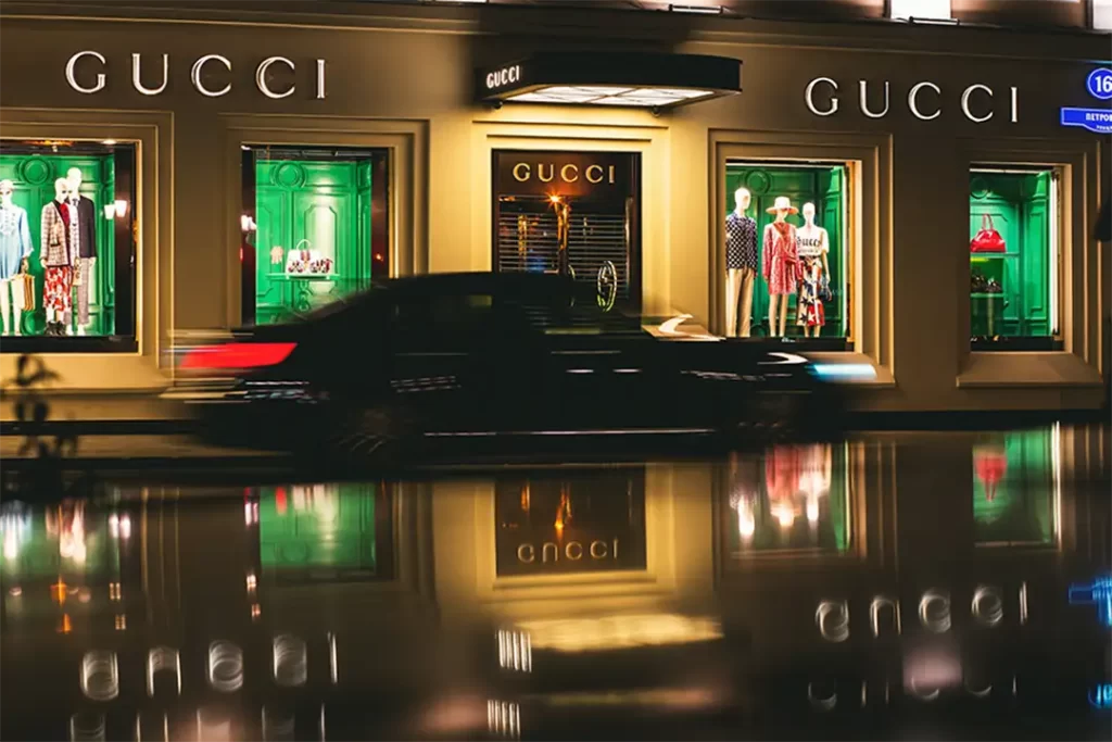 Vitrine da Gucci iluminada à noite, exibindo looks sofisticados que representam o luxo da Moda Italiana contemporânea.