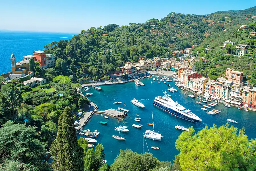 Vista panorâmica de Portofino, na Ligúria, com iates e barcos ancorados no porto — um dos destinos mais encantadores para passeios de barco na Itália.
