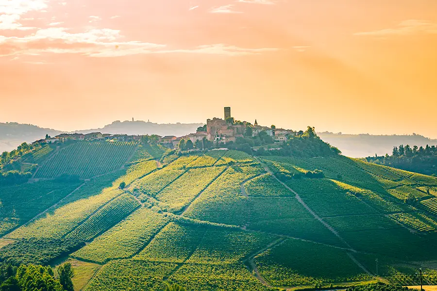 Vila de Barolo no topo de uma colina no Piemonte cercada por vinhedos ao pôr do sol