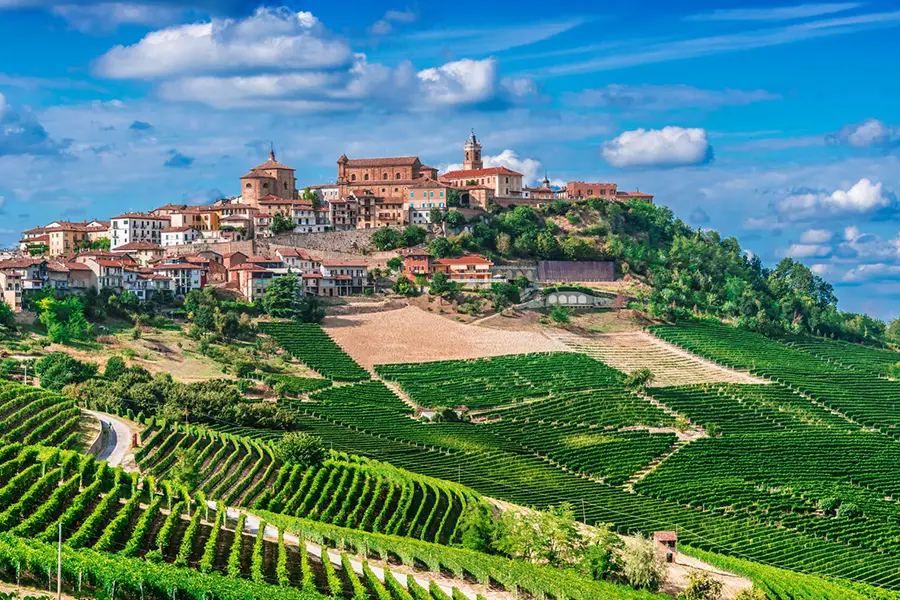 Vila de La Morra no topo da colina no Piemonte cercada por vinhedos verdes sob um céu azul