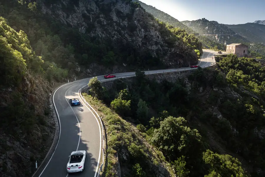 Estrada montanhosa sinuosa SS125 Orientale Sarda na Sardenha com carros passando entre penhascos rochosos e florestas verdes